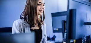 Happy smiling woman in modern office reading e-mails