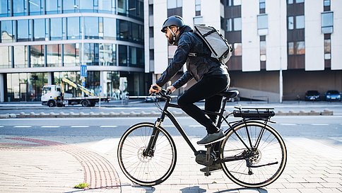 Male courier with bicycle delivering packages in city. Copy space.